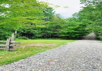 a gravel road with a fence and trees at chalet Ani in Piopolis