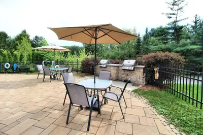 a patio with tables and chairs and an umbrella at Superbe condo - Navette de Ski Gratuite #102 in Bromont