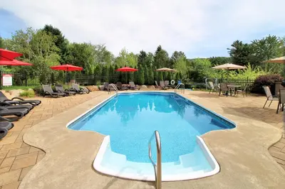 a large swimming pool with chairs and umbrellas at Superbe condo - Navette de Ski Gratuite #102 in Bromont