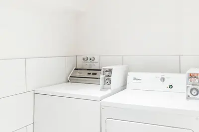 a white laundry room with a washer and dryer at Alt Hostel in Montréal