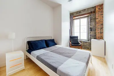 a bedroom with a bed and a brick wall at Alt Hostel in Montréal