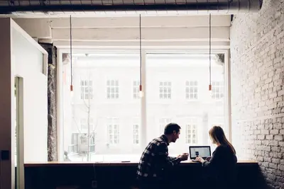 a man and a woman working on a laptop in front of a window at Alt Hostel in Montréal