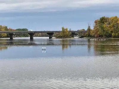 a bridge over a river with a bird in the water at Impeccable, modern, river view, renovated cottage in Laval