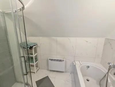 a white bathroom with a shower and a bath tub at Impeccable, modern, river view, renovated cottage in Laval