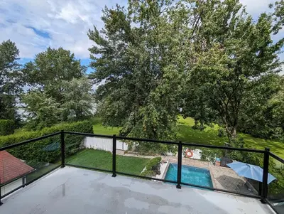 a view from the balcony of a house with a swimming pool at Impeccable, modern, river view, renovated cottage in Laval