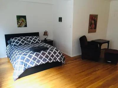 a bedroom with a bed and a chair on a wooden floor at Stylish Montreal Apartment: Comfortable Stay in the Golden Square Mile in Montréal