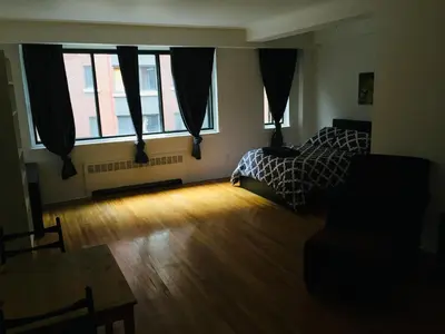 a bedroom with a bed and a table and windows at Stylish Montreal Apartment: Comfortable Stay in the Golden Square Mile in Montréal
