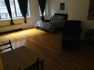 a bedroom with a bed and a wooden floor at Stylish Montreal Apartment: Comfortable Stay in the Golden Square Mile in Montréal