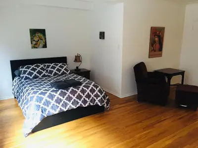 a bedroom with a bed and a chair on a wooden floor at Stylish Montreal Apartment: Comfortable Stay in the Golden Square Mile in Montréal