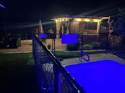a fence with a tub in a yard at night at Le Studio CITQ3O1849 in Saint Pierre de Broughton