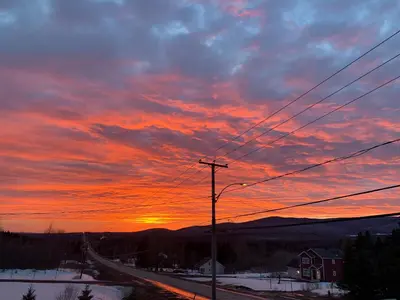 a sunset over a road with the sun setting at Gîte des étoiles in Notre-Dame-Des-Bois