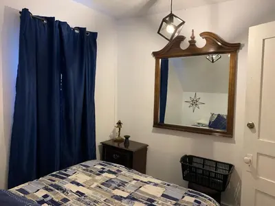 a bedroom with a bed with blue curtains and a mirror at Gîte des étoiles in Notre-Dame-Des-Bois