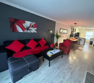 a living room with a couch and red pillows at Condo Phoenix prés du Lac Memphrémagog. in Magog-Orford