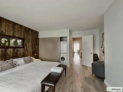 a bedroom with a large bed and a kitchen at Condo Phoenix prés du Lac Memphrémagog. in Magog-Orford