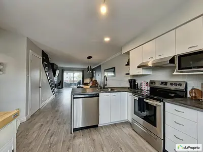 a kitchen with white cabinets and stainless steel appliances at Condo Phoenix prés du Lac Memphrémagog. in Magog-Orford
