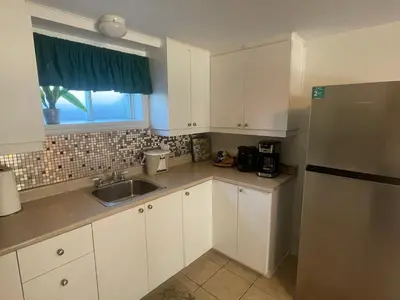 a kitchen with white cabinets and a sink and a window at Havre de paix in Laval