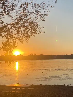 a sunset over a lake with a picnic table at Havre de paix in Laval