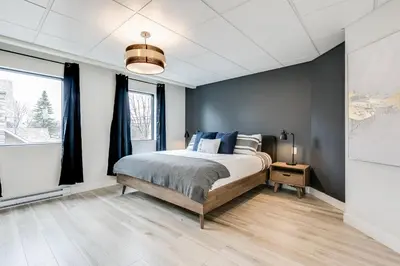 a bedroom with a bed and a large window at Complexe La Voûte by Gestion ELITE in Laval