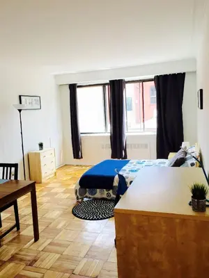 a bedroom with a bed and a table and windows at Stylish Montreal Apartment: Comfortable Stay in the Golden Square Mile in Montréal