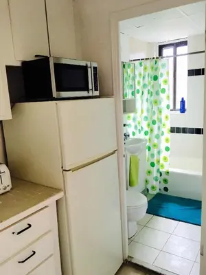 a small kitchen with a refrigerator and a microwave at Stylish Montreal Apartment: Comfortable Stay in the Golden Square Mile in Montréal