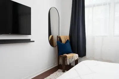 a bedroom with a mirror and a chair with a blue pillow at Luxury Old Montreal Parking with Yard Patio 10 Guests in Montréal