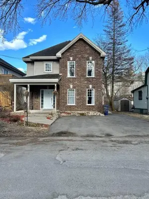 a brick house with a driveway in front of it at 3BR House 6 Guests Near Water in Laval