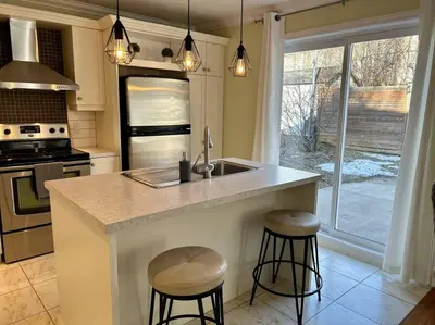a kitchen with a counter with two stools and a sink at 3BR House 6 Guests Near Water in Laval