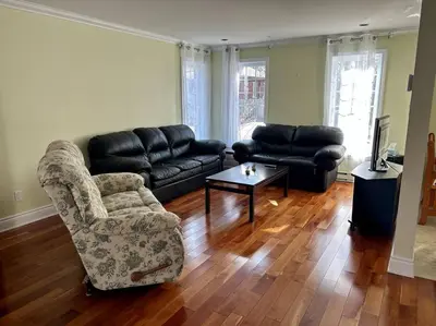 a living room with a couch and a chair and a table at 3BR House 6 Guests Near Water in Laval