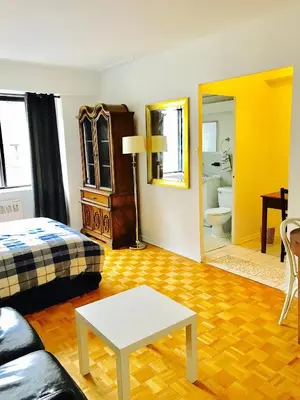 a room with a bed and a table and a mirror at Stylish Montreal Apartment: Comfortable Stay in the Golden Square Mile in Montréal