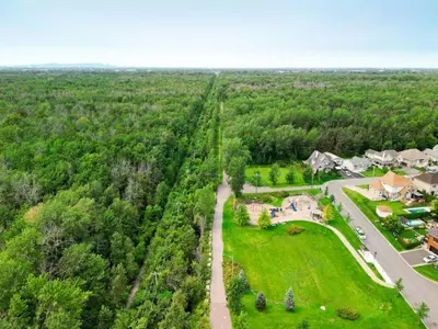 an aerial view of a house with a road and trees at L'Oasis Urbaine in Saint-Hubert
