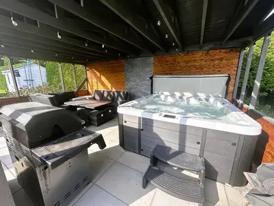 a hot tub and a grill on a patio at L'Oasis Urbaine in Saint-Hubert