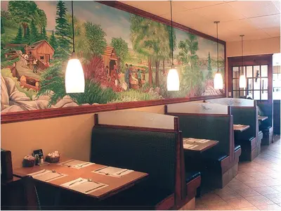 a dining room with tables and a large painting on the wall at Travelodge by Wyndham Drummondville in Drummondville