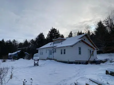 a white house with snow on top of it at Le Highwater - Cabin in Mansonville