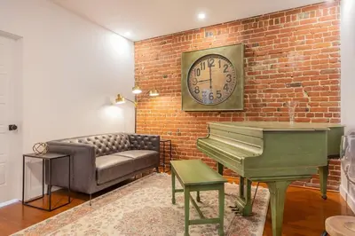a living room with a couch and a clock and a piano at L'exclusif du Plateau in Montréal