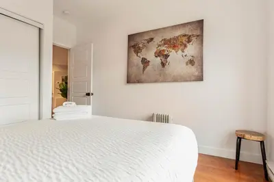 a bedroom with a white bed and a painting on the wall at L'exclusif du Plateau in Montréal