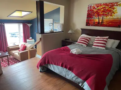 a bedroom with a large bed with a red blanket at Auberge et Chalets sur le Lac in Lac-Mégantic
