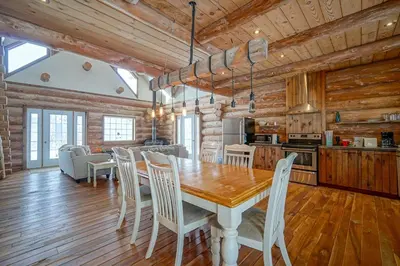 a kitchen and dining room with a wooden table and chairs at Chalet en bois rond des Perséides in Saint-Isidore dʼAuckland