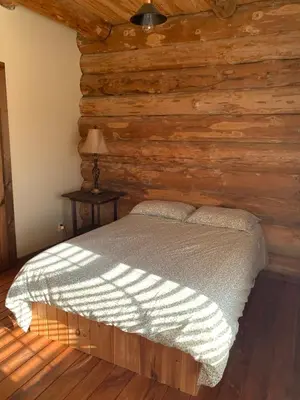 a bedroom with a bed in a log cabin at Chalet en bois rond des Perséides in Saint-Isidore dʼAuckland