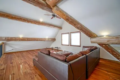 a living room with a couch and wooden floors at Chalet en bois rond des Perséides in Saint-Isidore dʼAuckland