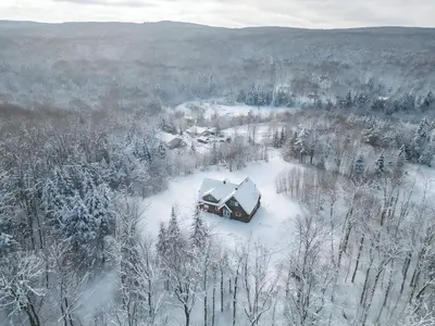 an aerial view of a house in the snow at Chalet en bois rond des Perséides in Saint-Isidore dʼAuckland