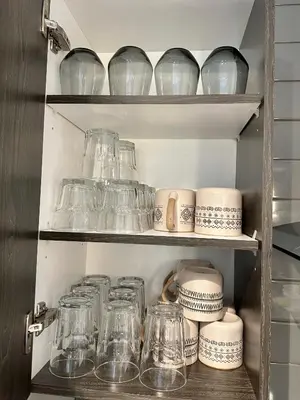 a cupboard filled with glass jars and plates at Appartment 2BR 4 beds AC wi-Fi Smart TV FreeParking in Laval