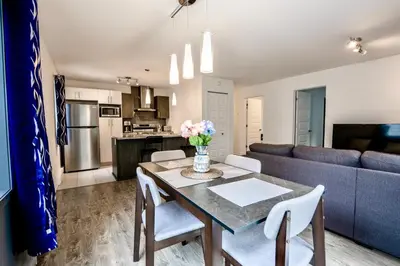 a kitchen and living room with a table and a couch at Appartment 2BR 4 beds AC wi-Fi Smart TV FreeParking in Laval