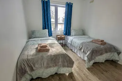 two beds in a room with blue curtains at Peaceful Getaway in Laval