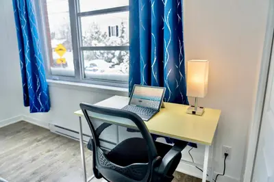 a desk with a laptop on it in front of a window at Peaceful Getaway in Laval