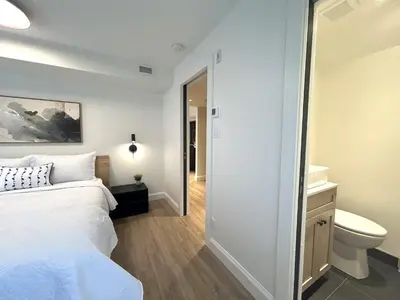 a bedroom with a white bed and a bathroom at Le Héron - Studios Nature in Magog-Orford