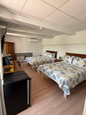 a hotel room with two beds and a television at Hostellerie du Suroît in Beauharnois
