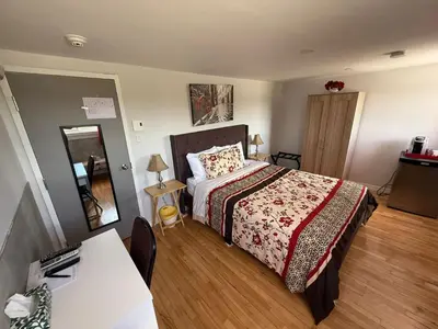 a bedroom with a bed and a table and a mirror at Hostellerie du Suroît in Beauharnois