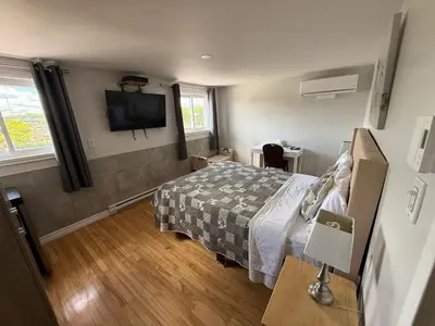 a bedroom with a bed and a flat screen tv at Hostellerie du Suroît in Beauharnois