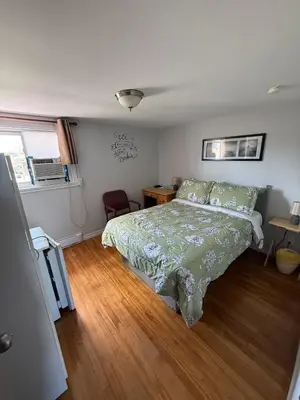 a bedroom with a bed and a wooden floor at Hostellerie du Suroît in Beauharnois