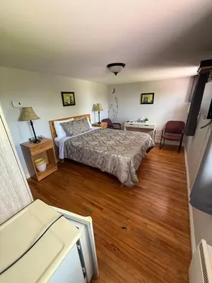 a bedroom with a bed and a wooden floor at Hostellerie du Suroît in Beauharnois